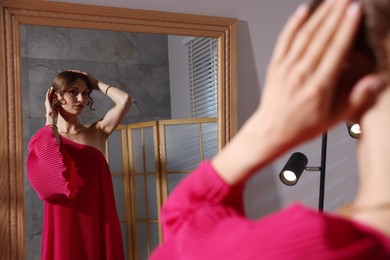 Photo of Beautiful woman getting ready near mirror indoors