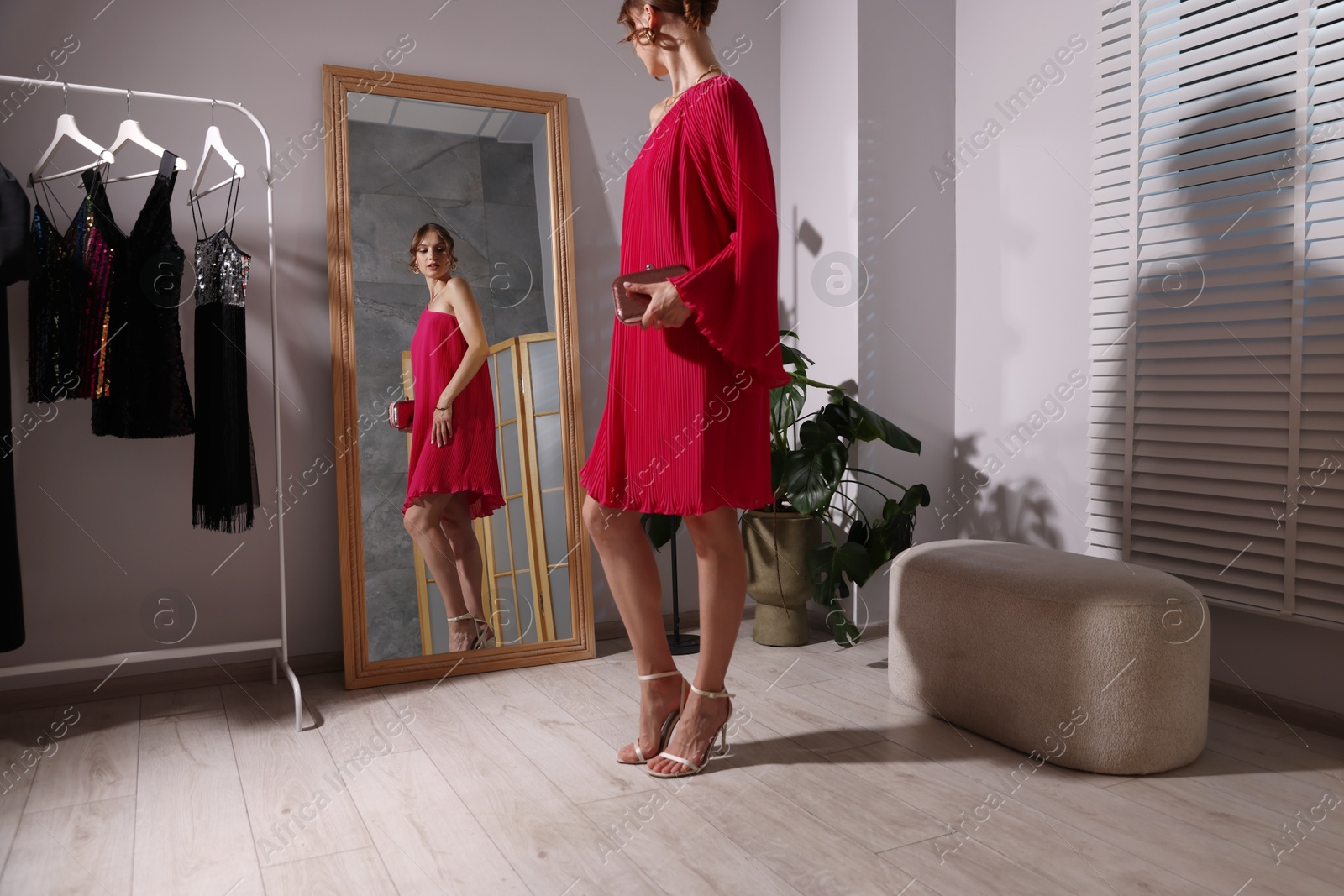 Beautiful woman with stylish bag getting ready near mirror indoors Photo of Beautiful woman with stylish bag getting ready near mirror indoors
