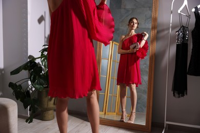 Photo of Beautiful woman with stylish bag getting ready near mirror indoors