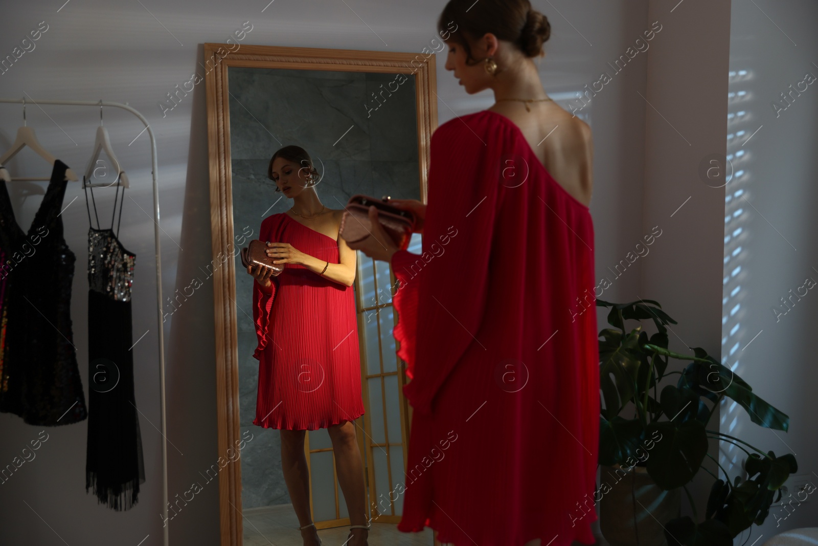 Beautiful woman with stylish bag getting ready near mirror indoors Photo of Beautiful woman with stylish bag getting ready near mirror indoors