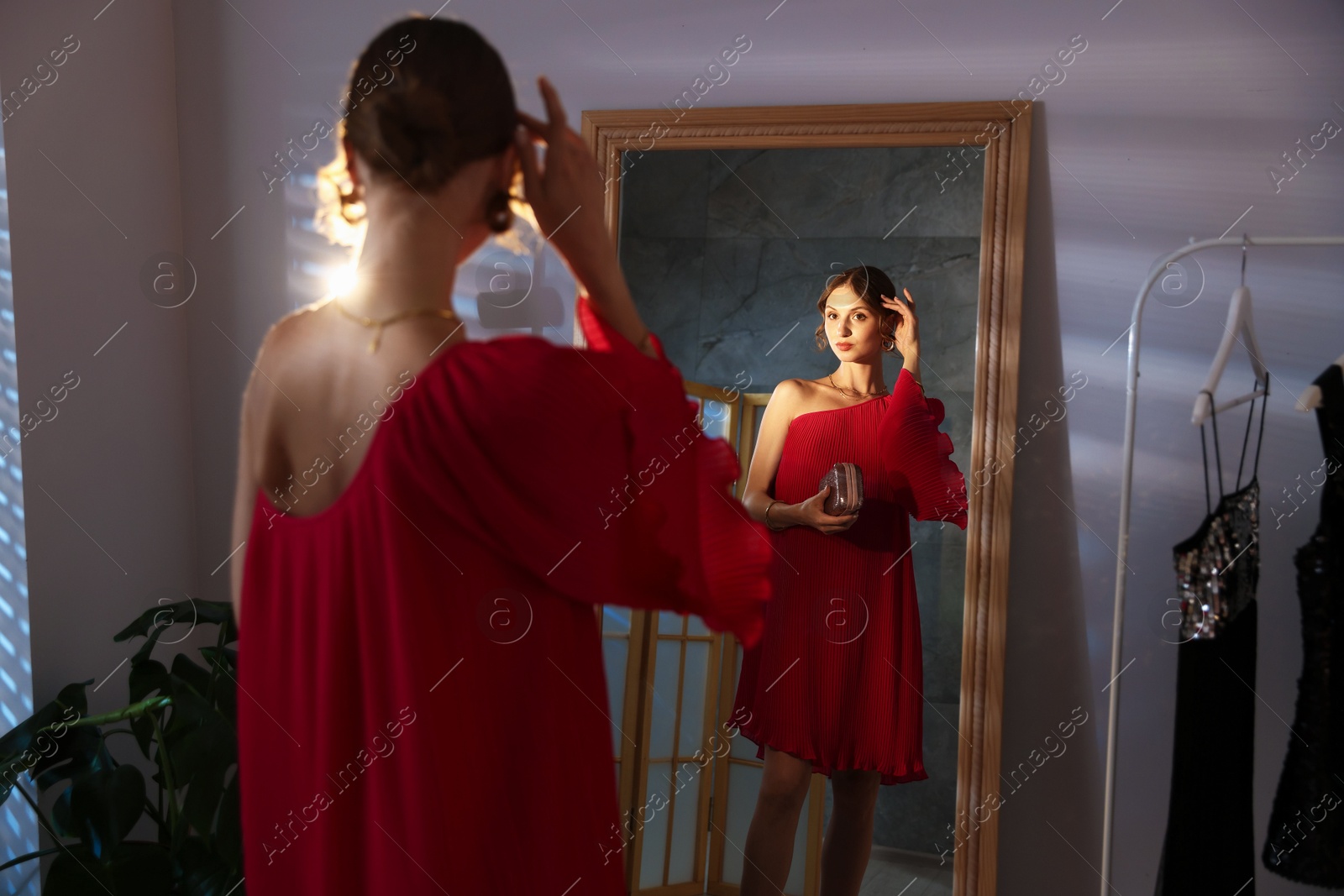 Beautiful woman with stylish bag getting ready near mirror indoors Photo of Beautiful woman with stylish bag getting ready near mirror indoors