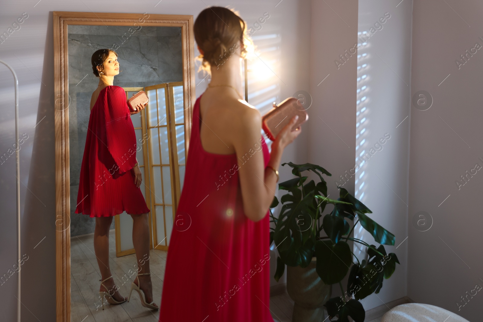 Beautiful woman with stylish bag getting ready near mirror indoors Photo of Beautiful woman with stylish bag getting ready near mirror indoors