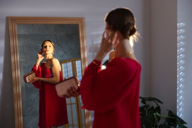 Photo of Beautiful woman with stylish bag getting ready near mirror indoors