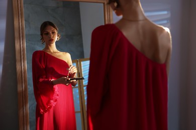 Photo of Beautiful woman applying makeup while getting ready near mirror indoors