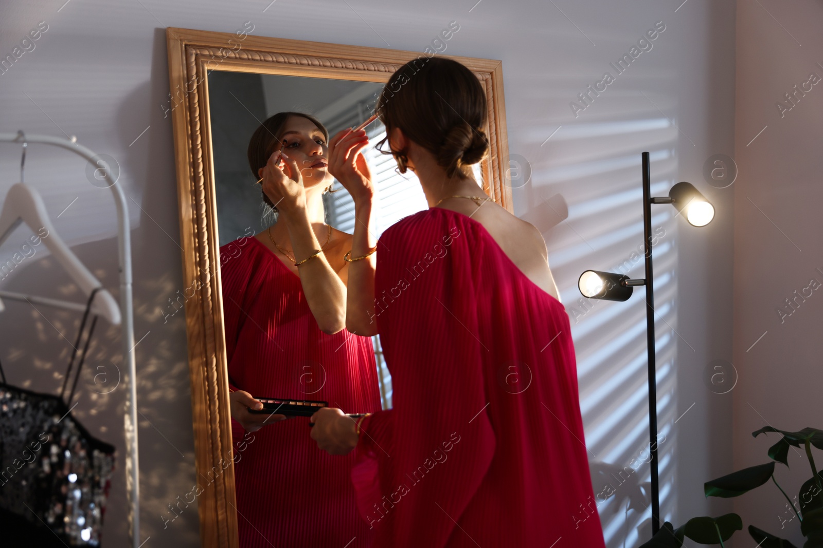 Beautiful woman applying makeup while getting ready near mirror indoors Photo of Beautiful woman applying makeup while getting ready near mirror indoors