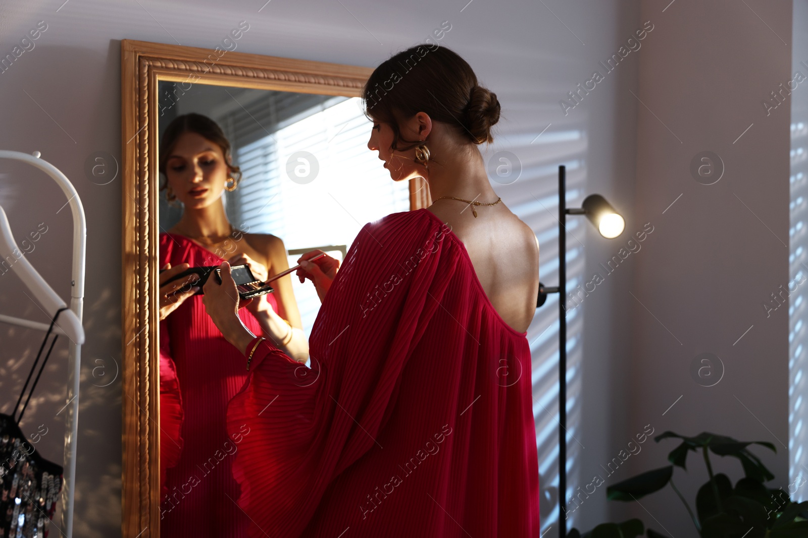 Beautiful woman applying makeup while getting ready near mirror indoors Photo of Beautiful woman applying makeup while getting ready near mirror indoors