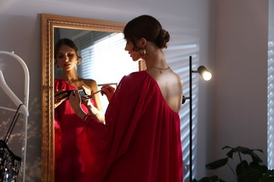 Photo of Beautiful woman applying makeup while getting ready near mirror indoors