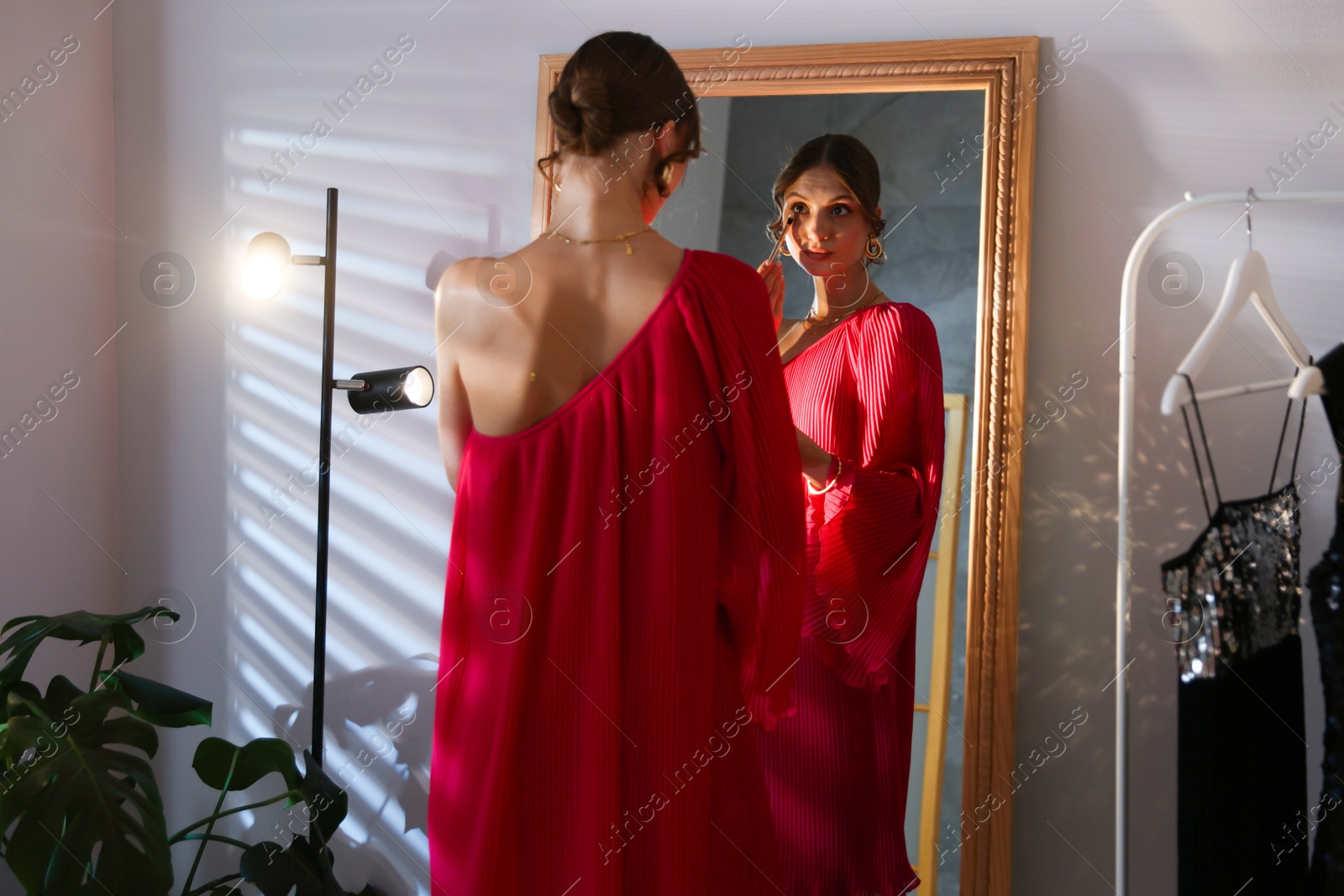 Beautiful woman applying makeup while getting ready near mirror indoors Photo of Beautiful woman applying makeup while getting ready near mirror indoors