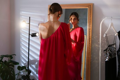 Photo of Beautiful woman applying makeup while getting ready near mirror indoors