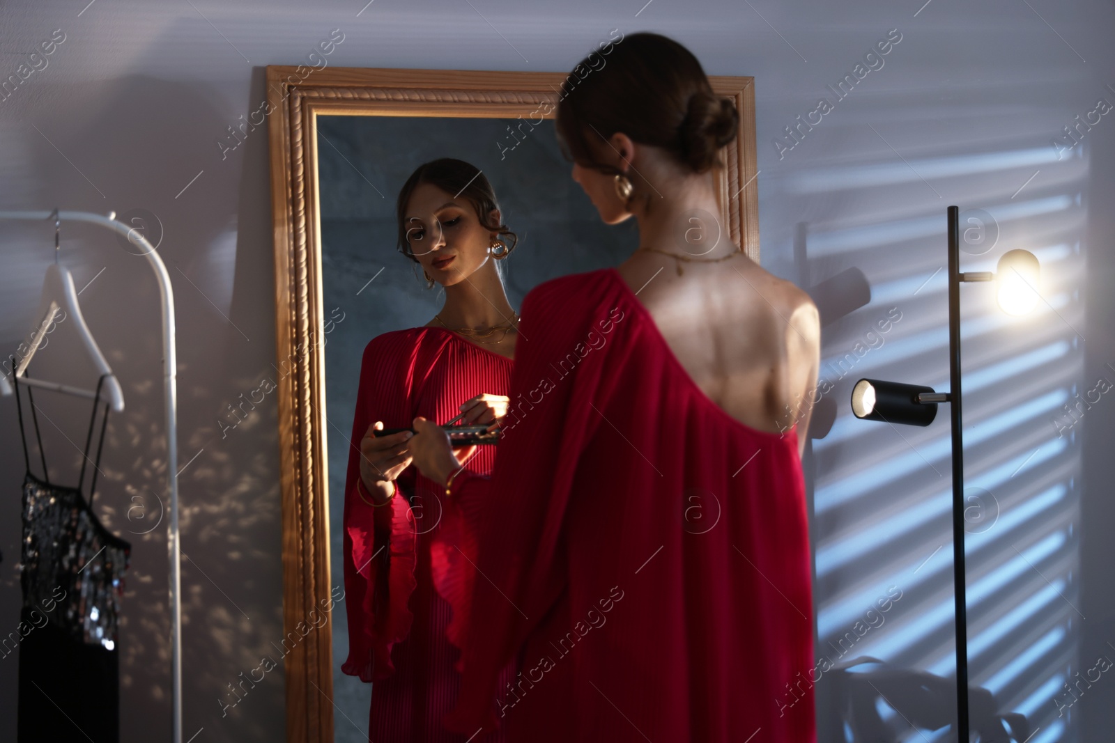 Beautiful woman applying makeup while getting ready near mirror indoors Photo of Beautiful woman applying makeup while getting ready near mirror indoors