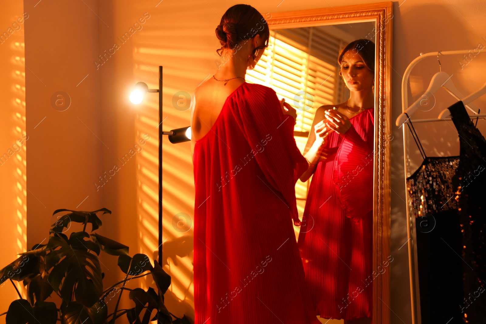 Beautiful woman with lipstick getting ready near mirror indoors Photo of Beautiful woman with lipstick getting ready near mirror indoors