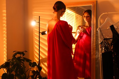 Photo of Beautiful woman with lipstick getting ready near mirror indoors