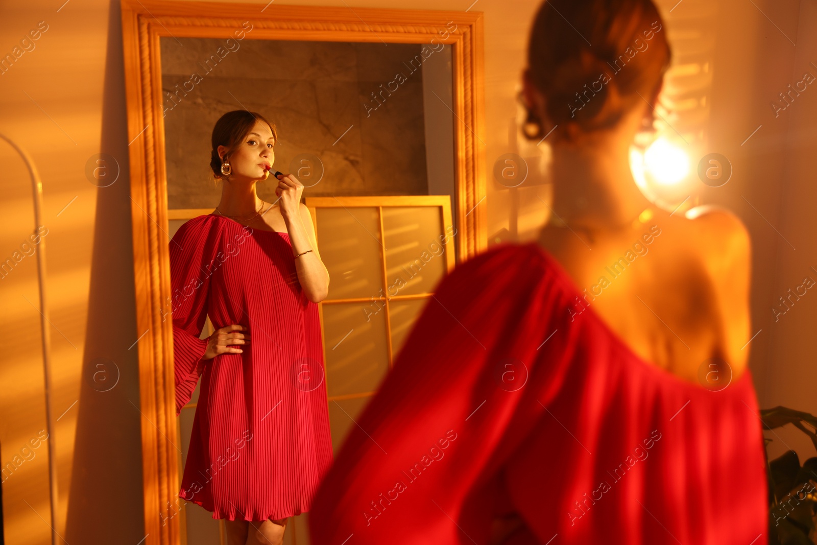 Beautiful woman applying lipstick while getting ready near mirror indoors Photo of Beautiful woman applying lipstick while getting ready near mirror indoors