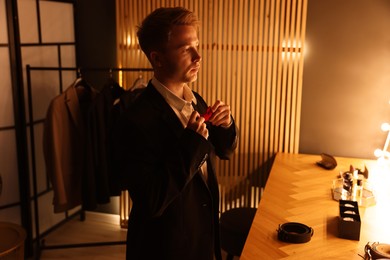 Photo of Man adjusting bow tie while getting ready indoors