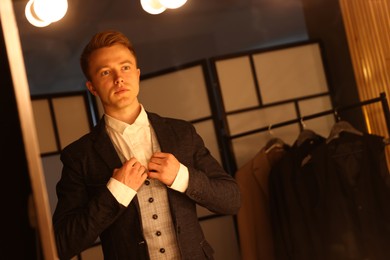 Photo of Man in stylish outfit getting ready near mirror indoors