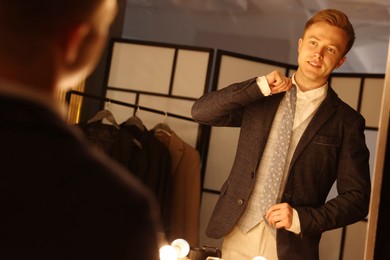Photo of Man with necktie getting ready near mirror indoors