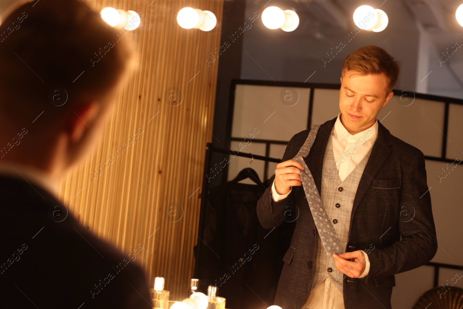 Man with necktie getting ready near mirror indoors Photo of Man with necktie getting ready near mirror indoors