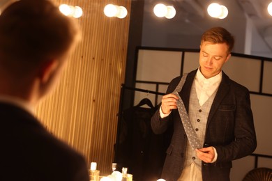 Photo of Man with necktie getting ready near mirror indoors