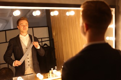 Photo of Man with necktie getting ready near mirror indoors