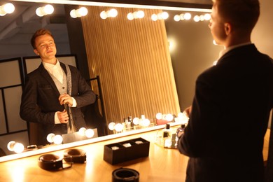 Photo of Man with necktie getting ready near mirror indoors