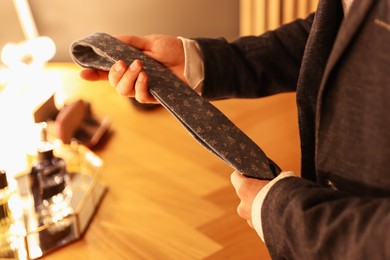 Photo of Man with necktie getting ready at dressing table indoors, closeup
