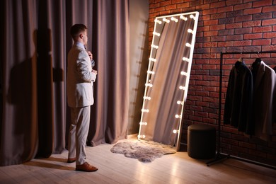 Photo of Handsome man getting ready near mirror indoors