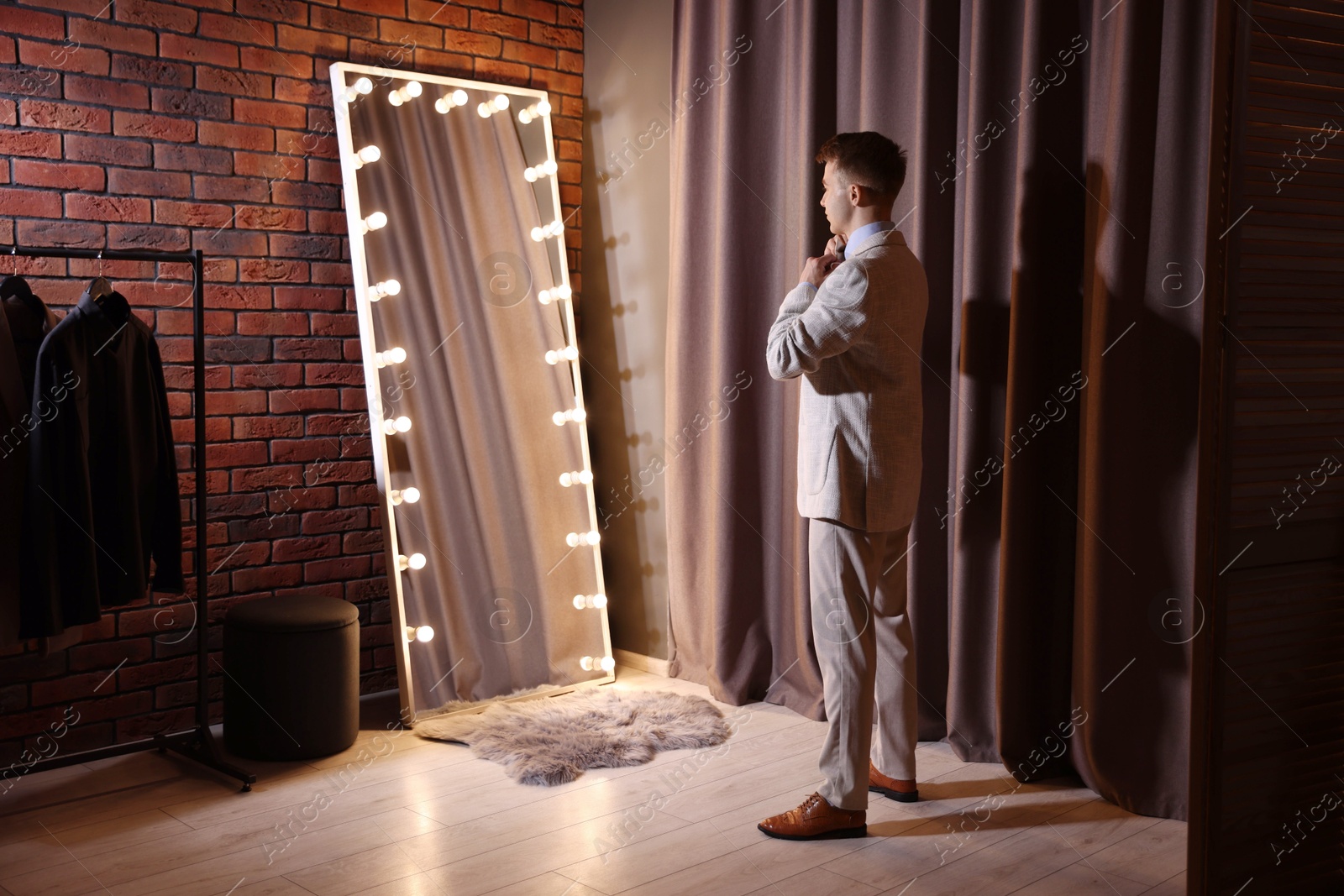 Handsome man getting ready near mirror indoors Photo of Handsome man getting ready near mirror indoors