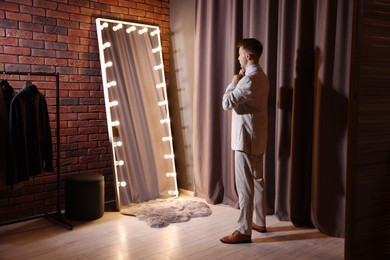 Photo of Handsome man getting ready near mirror indoors