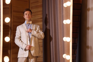 Photo of Handsome man getting ready near mirror indoors