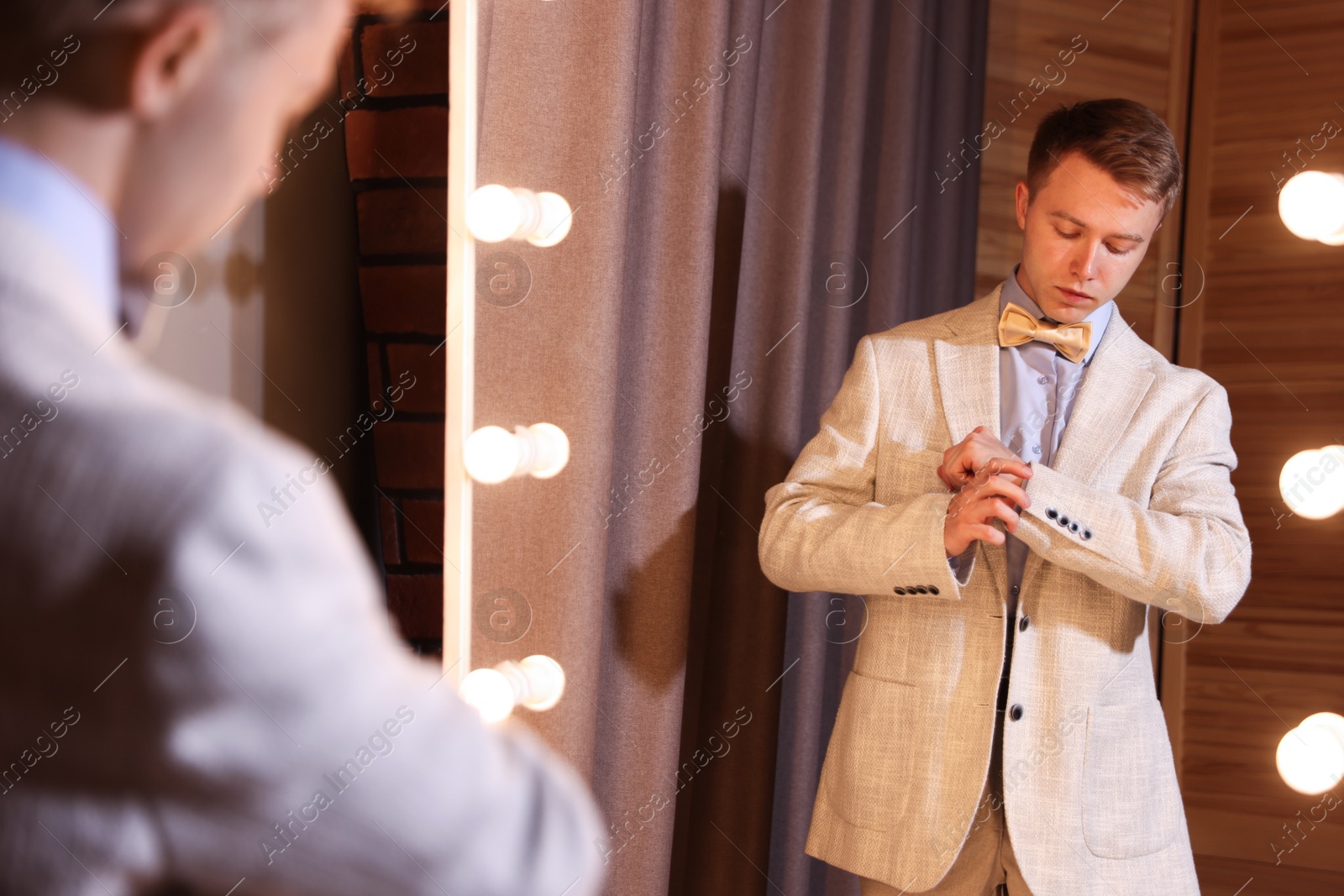 Handsome man getting ready near mirror indoors Photo of Handsome man getting ready near mirror indoors