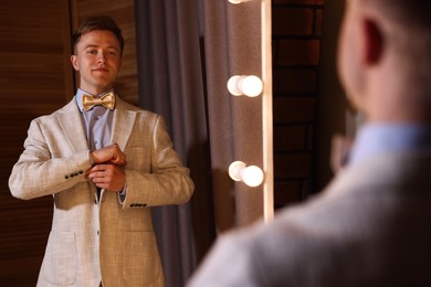 Photo of Handsome man getting ready near mirror indoors