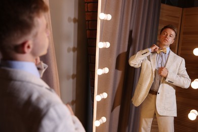 Photo of Handsome man getting ready near mirror indoors