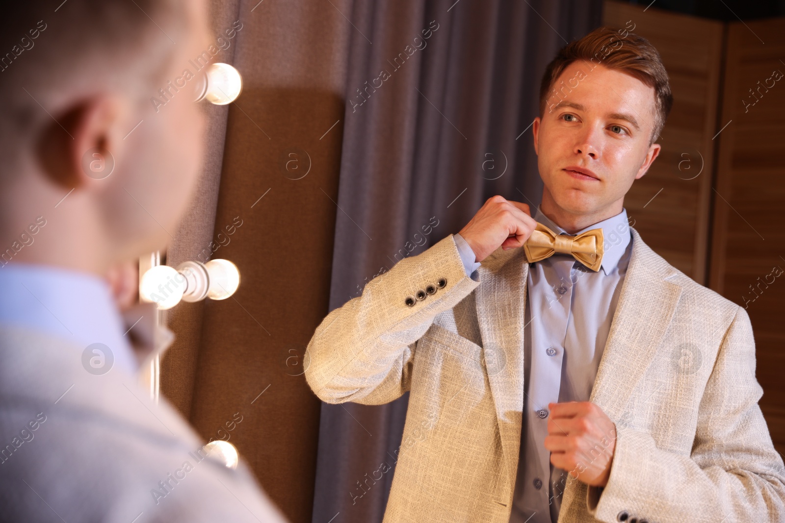 Handsome man getting ready near mirror indoors Photo of Handsome man getting ready near mirror indoors