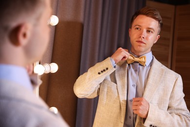 Photo of Handsome man getting ready near mirror indoors