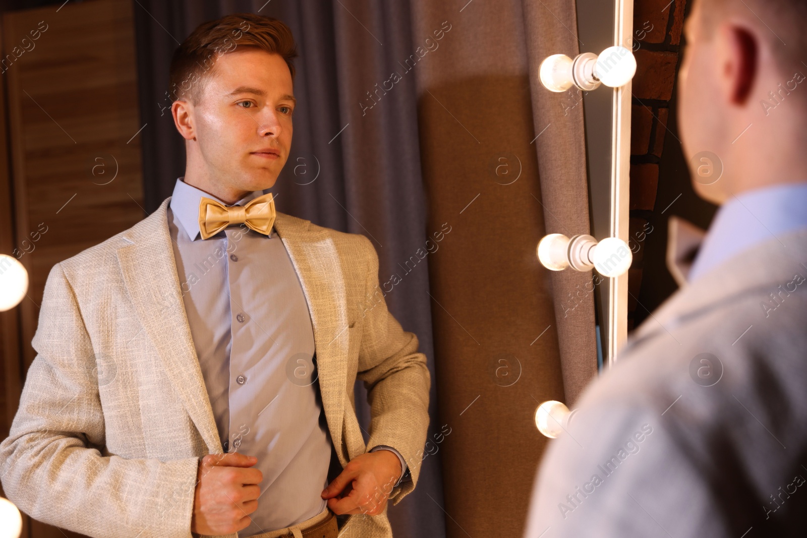 Handsome man getting ready near mirror indoors Photo of Handsome man getting ready near mirror indoors