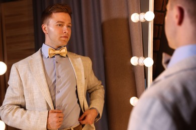 Photo of Handsome man getting ready near mirror indoors