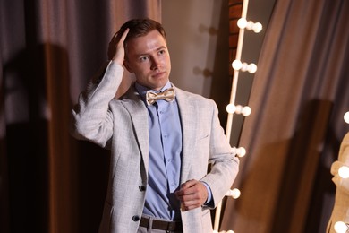 Photo of Handsome man getting ready near mirror indoors