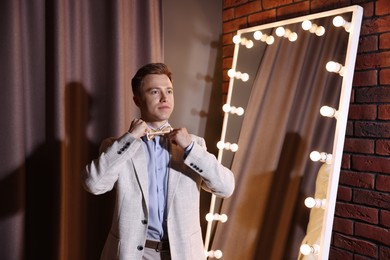 Photo of Handsome man getting ready near mirror indoors