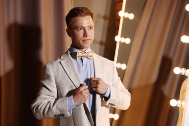 Photo of Handsome man getting ready near mirror indoors