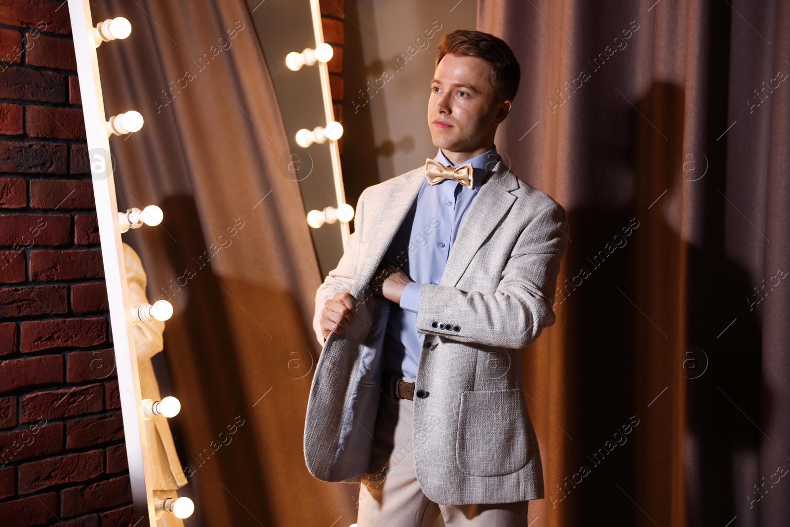 Handsome man getting ready near mirror indoors Photo of Handsome man getting ready near mirror indoors