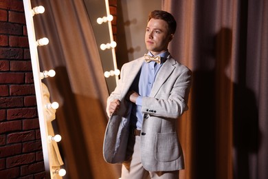 Photo of Handsome man getting ready near mirror indoors