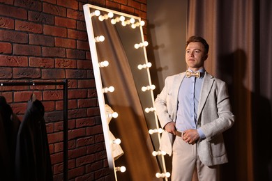 Photo of Handsome man getting ready near mirror indoors