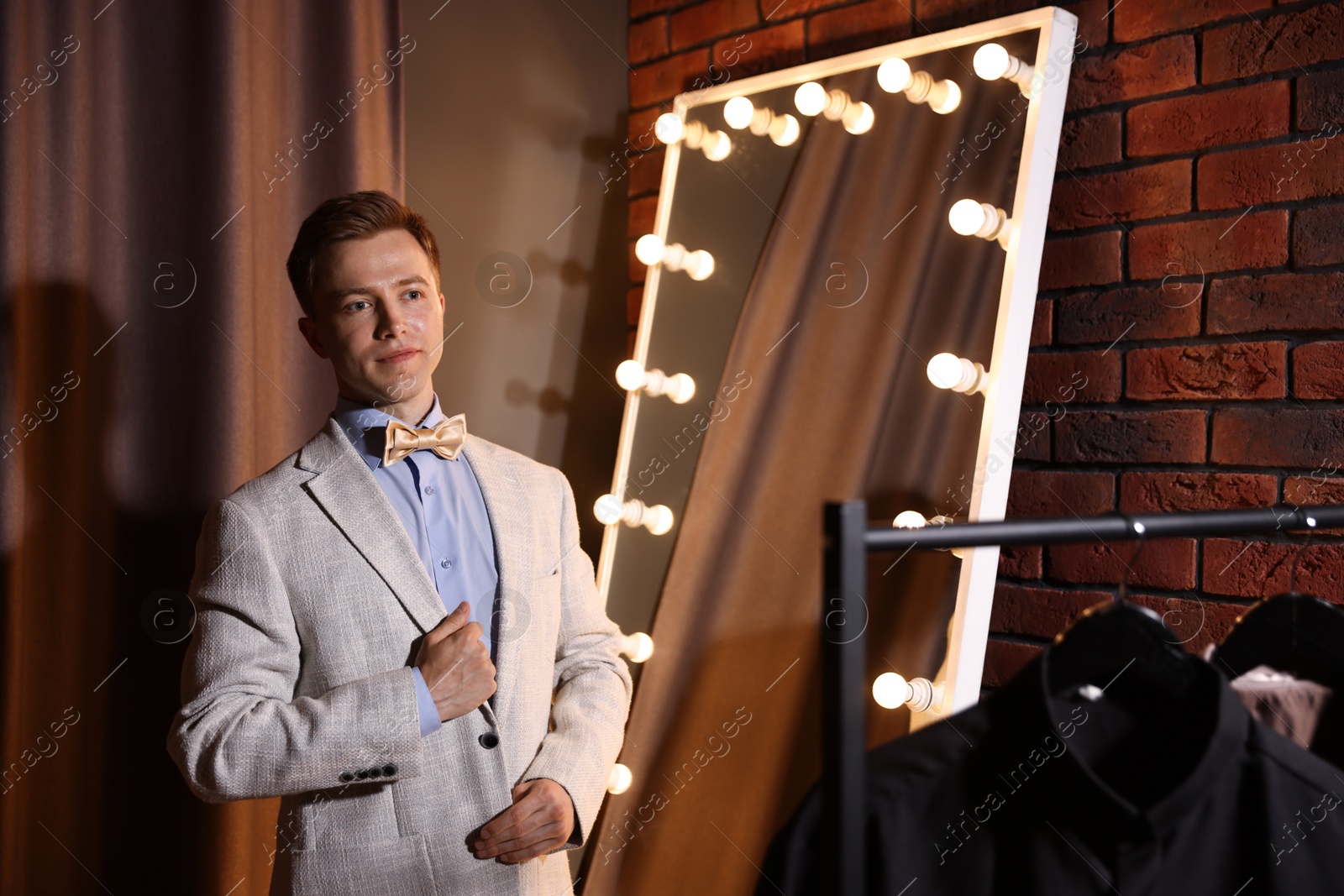 Handsome man getting ready near mirror indoors Photo of Handsome man getting ready near mirror indoors