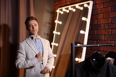 Photo of Handsome man getting ready near mirror indoors