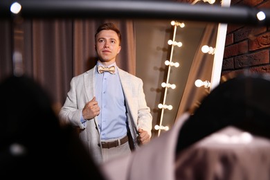 Photo of Handsome man getting ready near mirror indoors