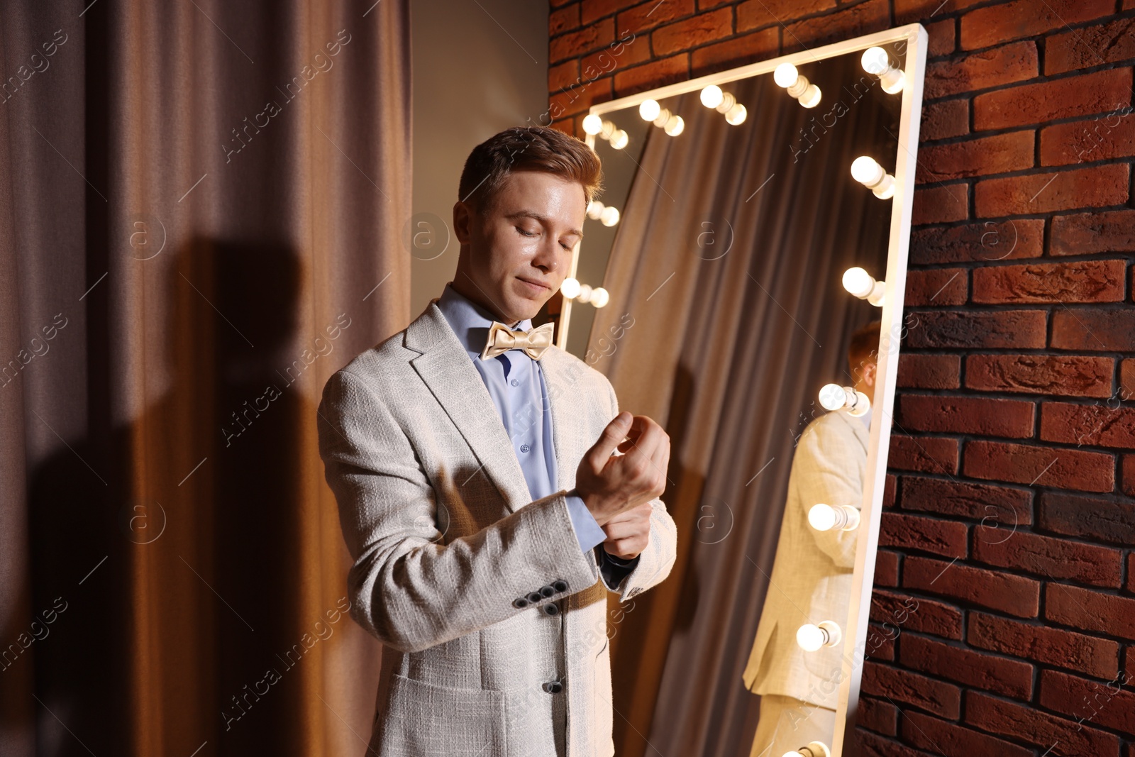 Handsome man getting ready near mirror indoors Photo of Handsome man getting ready near mirror indoors