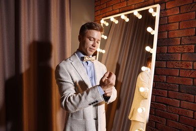 Photo of Handsome man getting ready near mirror indoors