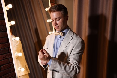 Photo of Handsome man getting ready near mirror indoors
