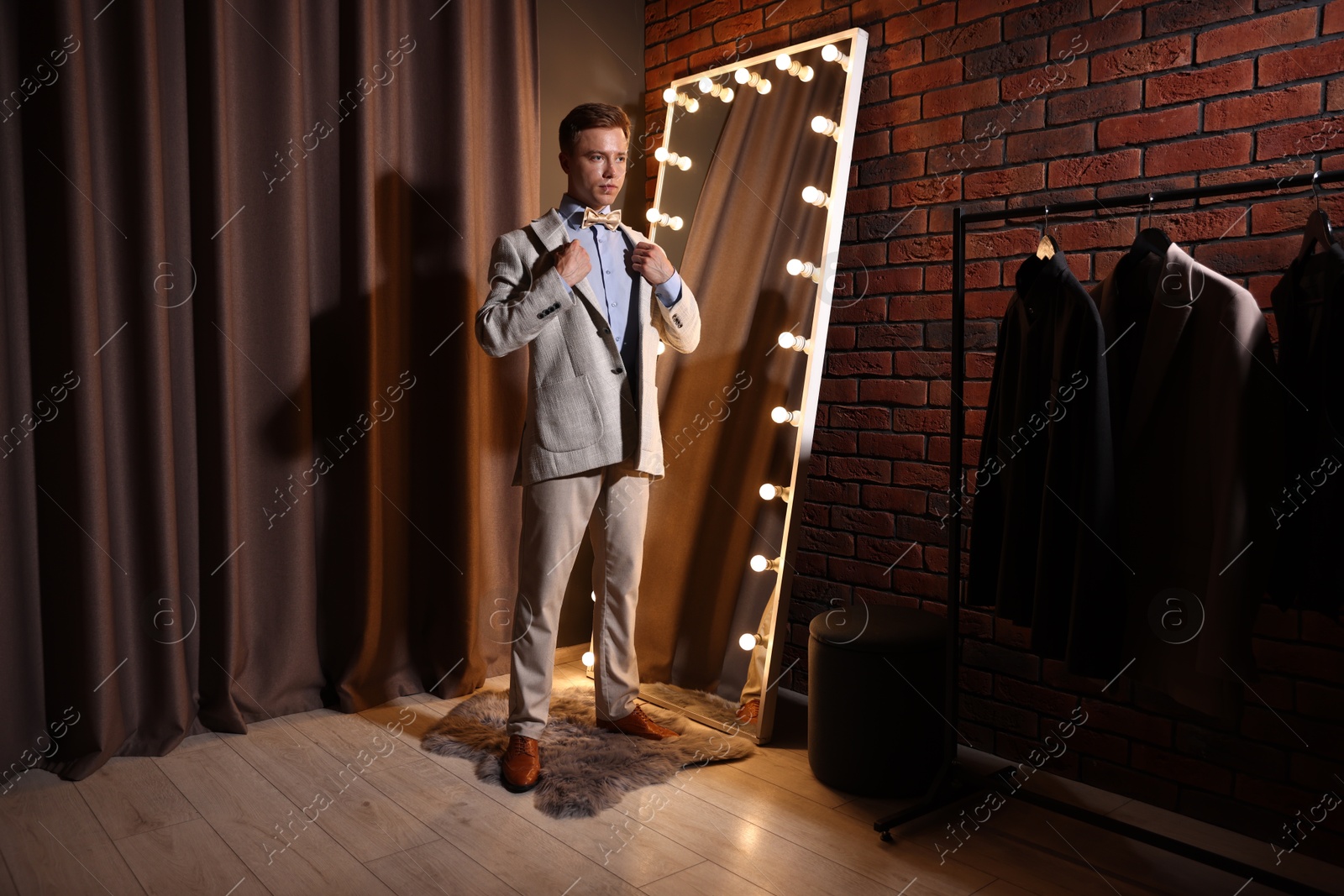 Handsome man getting ready near mirror indoors Photo of Handsome man getting ready near mirror indoors