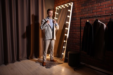 Photo of Handsome man getting ready near mirror indoors